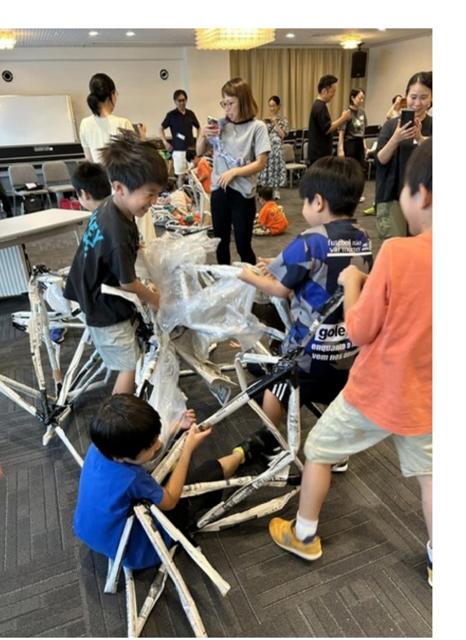 新聞紙とビニールで骨組みをつくる子どもたち